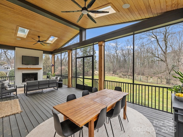 sunroom / solarium featuring an outdoor brick fireplace, wood ceiling, lofted ceiling with skylight, and ceiling fan