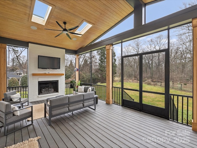 sunroom featuring an outdoor brick fireplace, ceiling fan, wooden ceiling, and vaulted ceiling with skylight