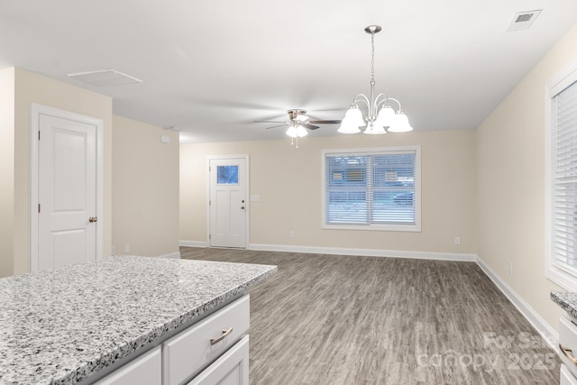 kitchen with light wood-style flooring, white cabinets, open floor plan, baseboards, and decorative light fixtures