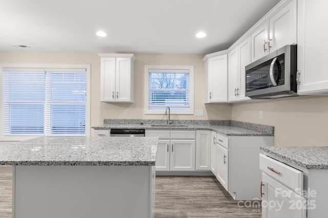 kitchen featuring stainless steel appliances, a sink, a center island, and white cabinets