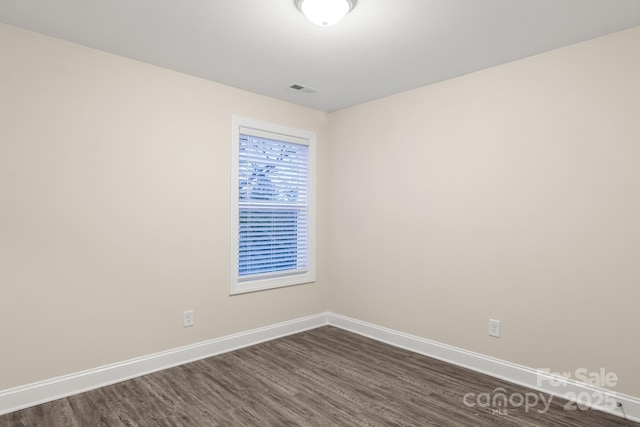 spare room featuring dark wood-style floors, visible vents, and baseboards