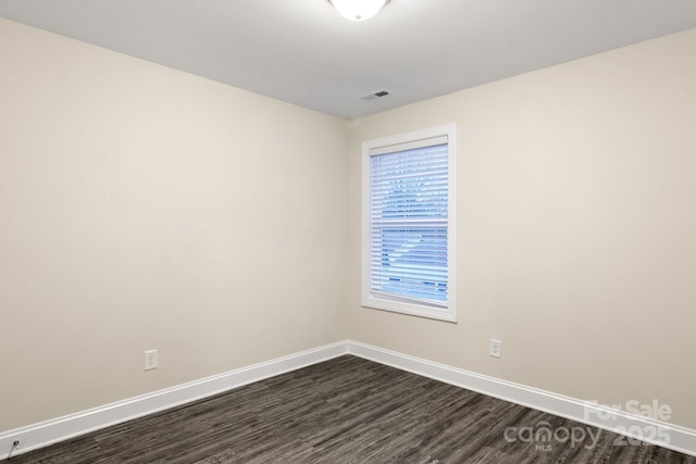 unfurnished room featuring baseboards, visible vents, and dark wood-style flooring