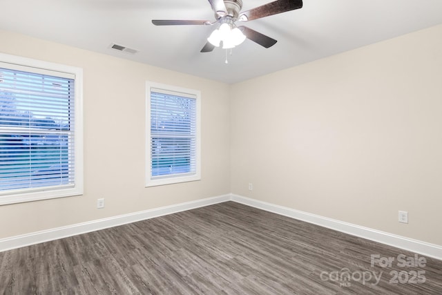 empty room featuring ceiling fan, dark wood-style flooring, visible vents, and baseboards