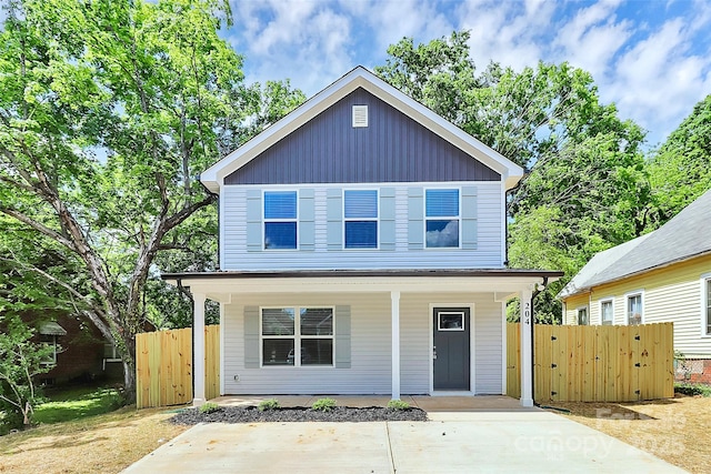 traditional-style home featuring covered porch, fence, and a gate
