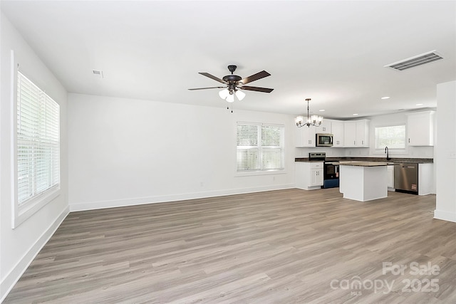 unfurnished living room featuring light wood-style floors, visible vents, baseboards, and a healthy amount of sunlight