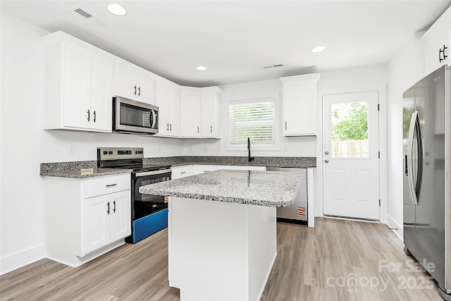kitchen with stone countertops, light wood-style flooring, visible vents, and appliances with stainless steel finishes