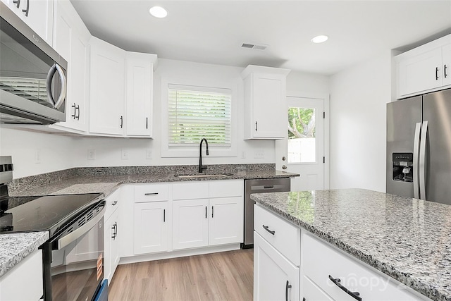 kitchen featuring stainless steel appliances, light stone counters, visible vents, and a sink