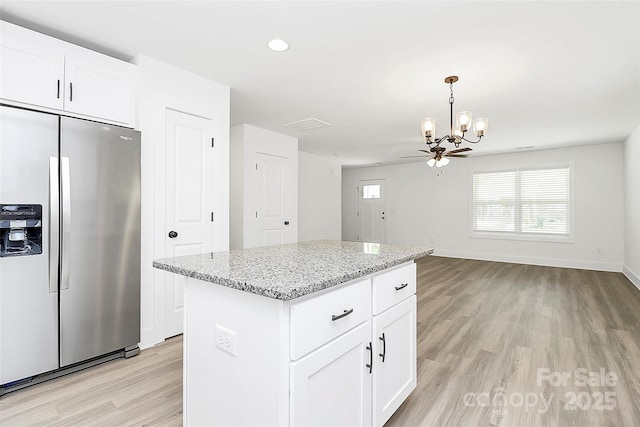 kitchen with light stone counters, white cabinets, light wood-type flooring, and stainless steel refrigerator with ice dispenser