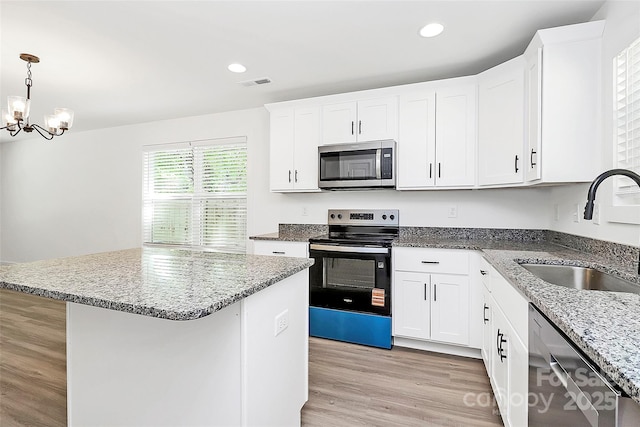 kitchen with appliances with stainless steel finishes, visible vents, light stone countertops, and a sink
