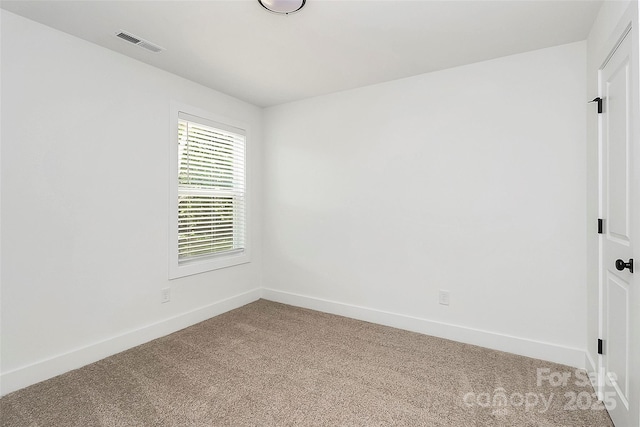 empty room featuring baseboards, visible vents, and light colored carpet
