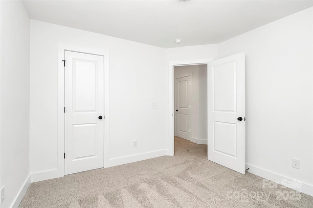unfurnished bedroom with light colored carpet and baseboards
