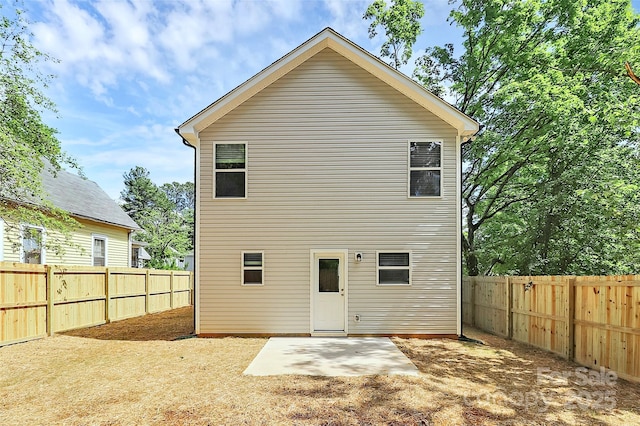 rear view of property with a fenced backyard and a patio