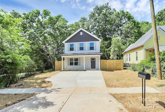 traditional-style home with a porch, fence, a gate, and driveway