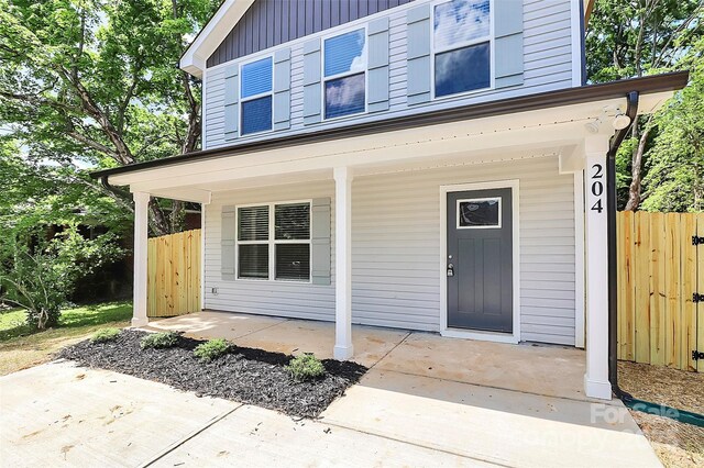 entrance to property featuring covered porch and fence
