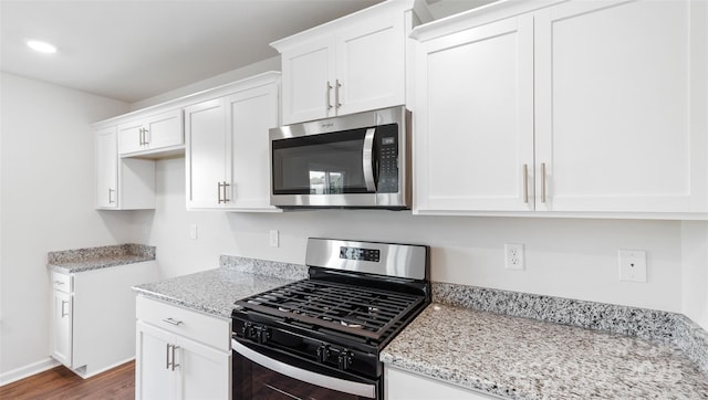 kitchen with light stone counters, stainless steel appliances, and white cabinets