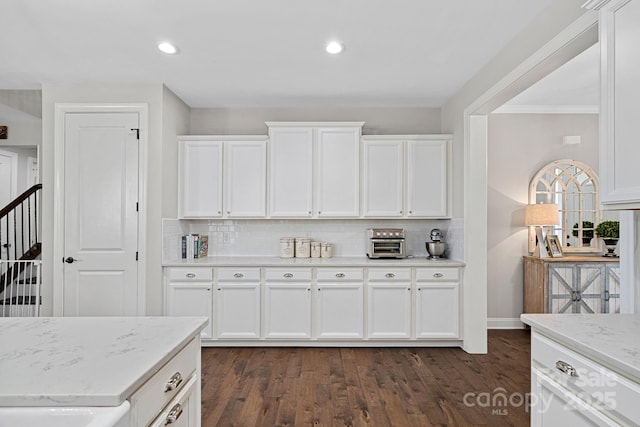 kitchen featuring tasteful backsplash, white cabinetry, dark wood-type flooring, and light stone counters