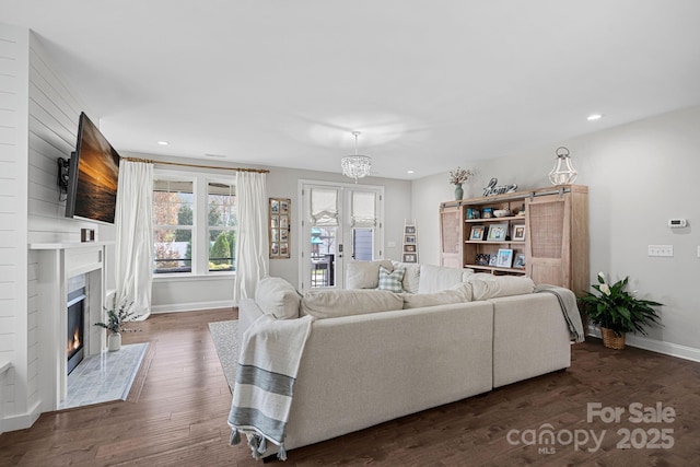 living room featuring dark hardwood / wood-style floors, an inviting chandelier, and a fireplace