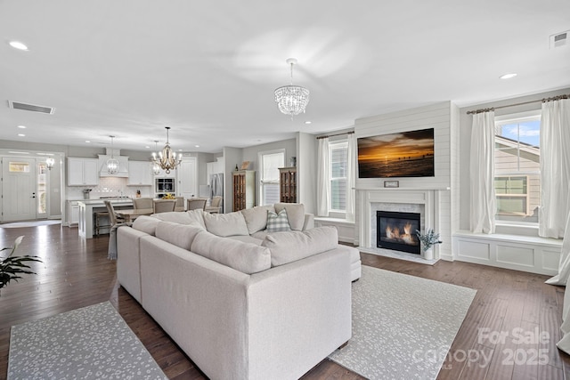 living room with dark hardwood / wood-style floors, a fireplace, and a chandelier