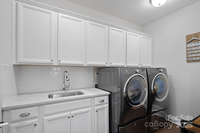 washroom featuring sink, washer and clothes dryer, and cabinets