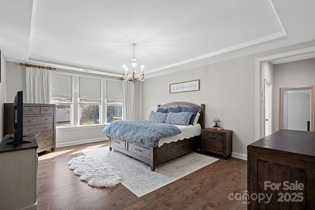 bedroom with dark hardwood / wood-style flooring, a notable chandelier, a tray ceiling, and ornamental molding