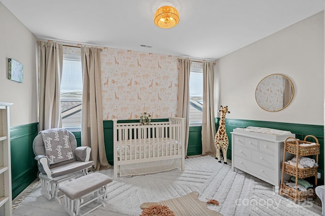 bedroom featuring a nursery area and light colored carpet