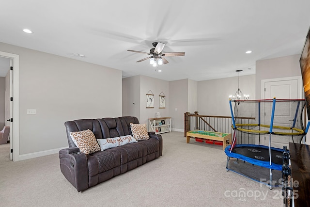 carpeted living room featuring ceiling fan with notable chandelier