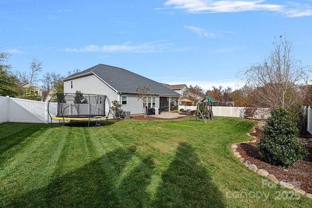 rear view of property with a trampoline, a yard, and a playground