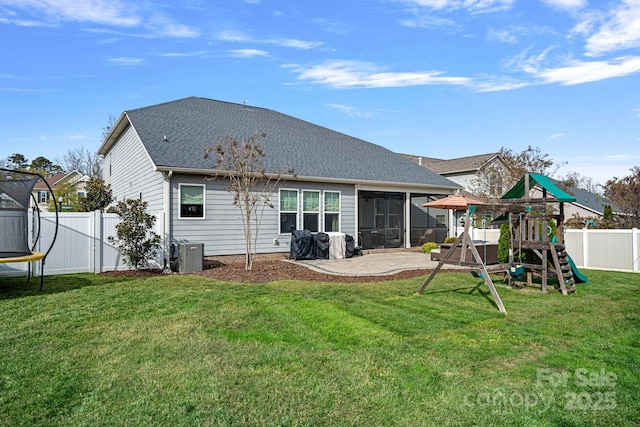 rear view of property with a trampoline, a yard, central AC, a patio area, and a playground