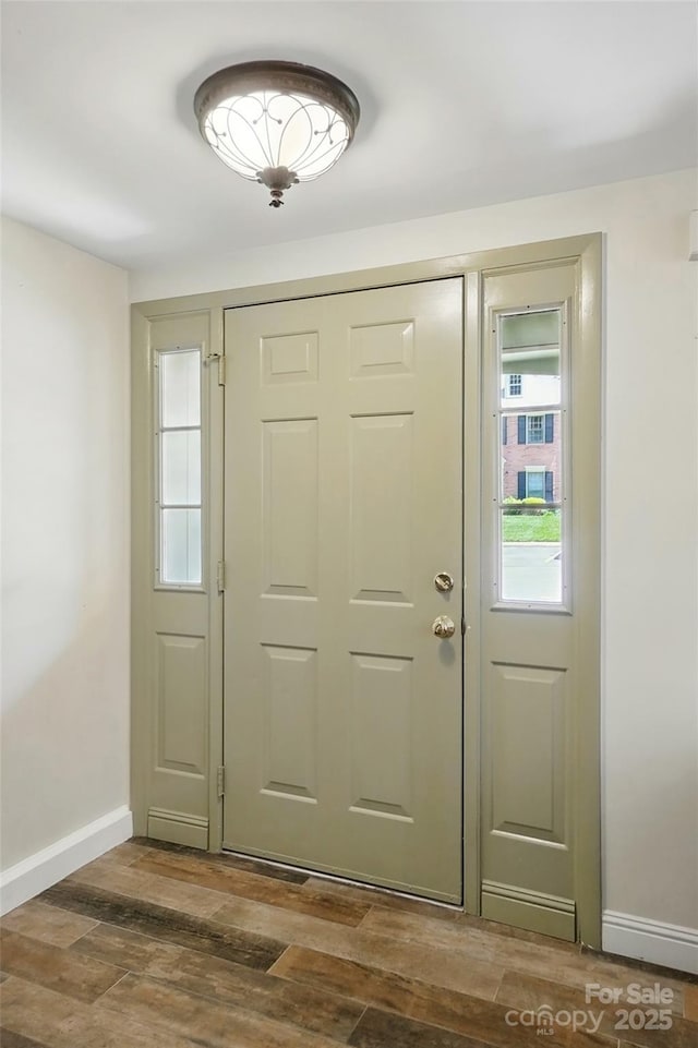 doorway featuring baseboards and wood finished floors