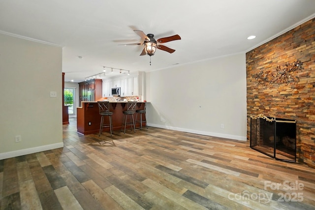 living room with a ceiling fan, crown molding, wood finished floors, track lighting, and baseboards