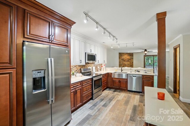 kitchen featuring a sink, light countertops, light wood-style flooring, stainless steel appliances, and backsplash