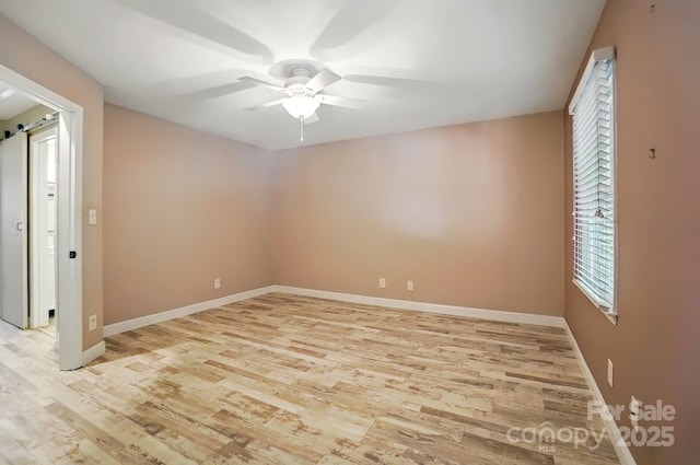 empty room with light wood-type flooring, a ceiling fan, and baseboards