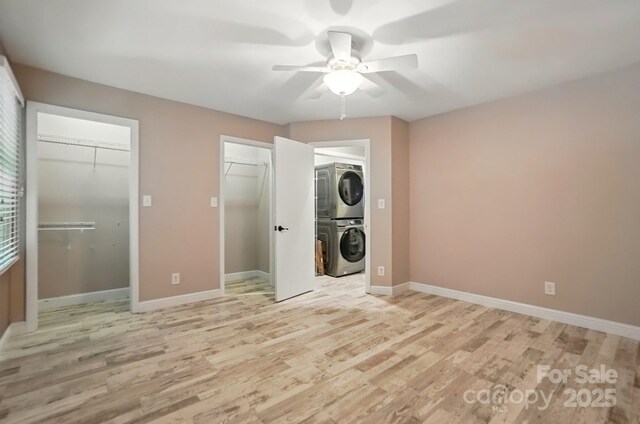 washroom featuring ceiling fan, light wood finished floors, stacked washer / dryer, and laundry area