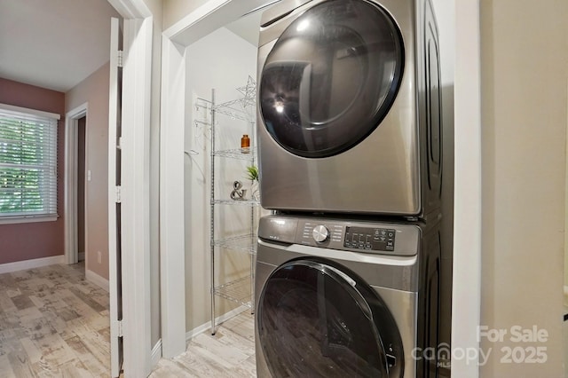 laundry room with stacked washing maching and dryer, baseboards, light wood-style floors, and laundry area