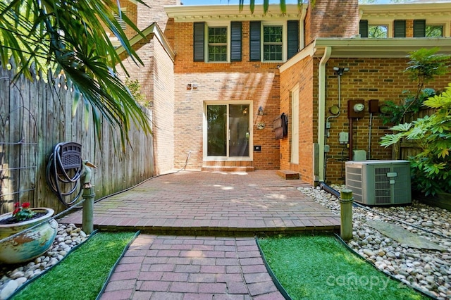 rear view of property with fence, cooling unit, a patio area, and brick siding