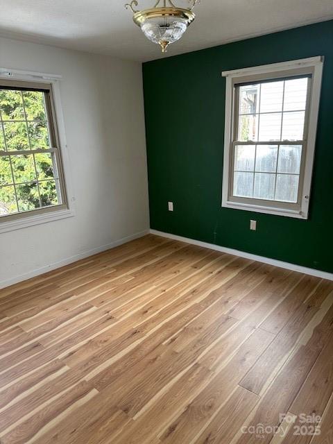 16 Castle St, Asheville, NC 28803 - empty room with a notable chandelier, baseboards, and light wood finished floors