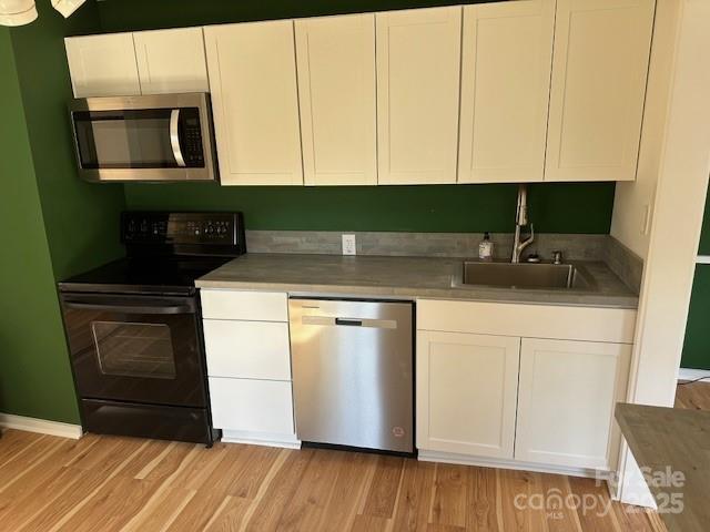 16 Castle St, Asheville, NC 28803 - kitchen featuring white cabinets, a sink, stainless steel appliances, and light wood finished floors