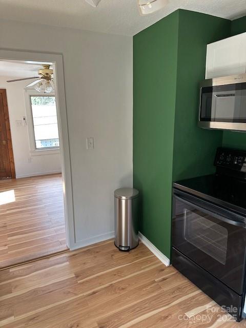 16 Castle St, Asheville, NC 28803 - kitchen featuring baseboards, ceiling fan, stainless steel microwave, black range with electric cooktop, and light wood-style floors