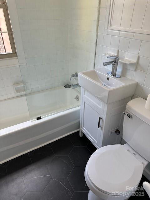 16 Castle St, Asheville, NC 28803 - bathroom with tile patterned flooring, vanity, tile walls, toilet, and bathing tub / shower combination