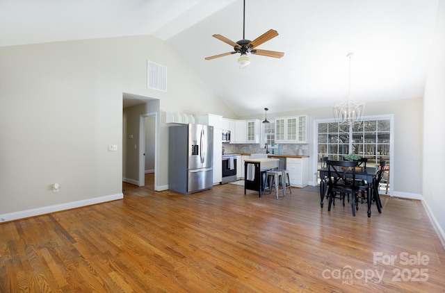 interior space featuring ceiling fan with notable chandelier, high vaulted ceiling, and hardwood / wood-style floors