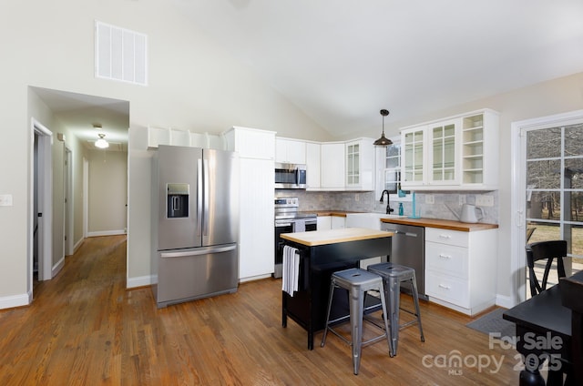 kitchen featuring stainless steel appliances, white cabinetry, and hanging light fixtures