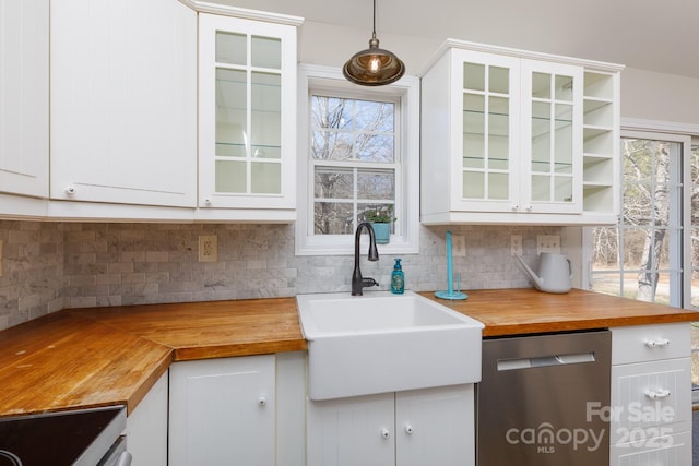 kitchen with appliances with stainless steel finishes, decorative light fixtures, white cabinetry, butcher block counters, and sink