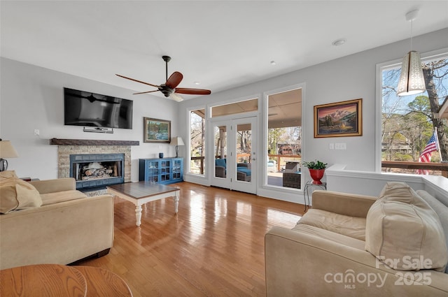 living room featuring a fireplace, wood finished floors, and ceiling fan