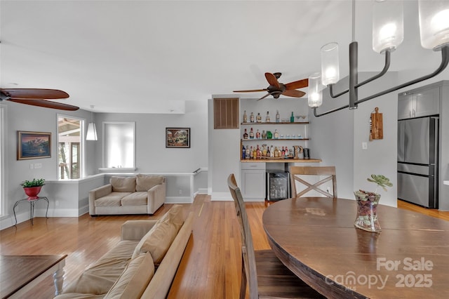 interior space featuring visible vents, a bar, light wood finished floors, baseboards, and ceiling fan