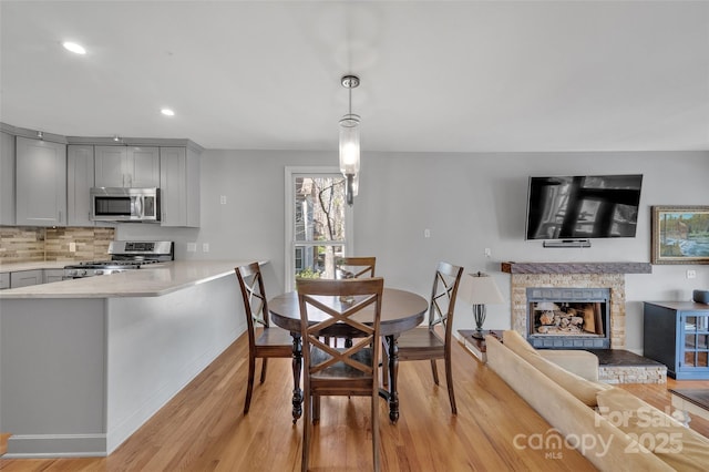 dining area featuring recessed lighting, light wood-style flooring, a fireplace, and baseboards