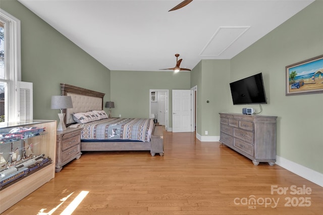 bedroom with baseboards, ceiling fan, attic access, lofted ceiling, and light wood-style flooring