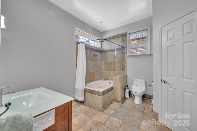 bathroom featuring vanity, stone tile floors, baseboards, toilet, and tiled shower / bath