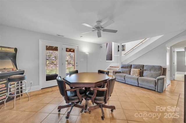 dining space featuring visible vents, a ceiling fan, light tile patterned floors, baseboards, and stairs