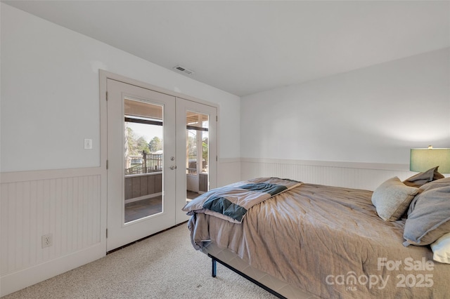 bedroom featuring visible vents, carpet, wainscoting, french doors, and access to outside