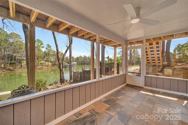 unfurnished sunroom with a ceiling fan, a water view, and a wealth of natural light